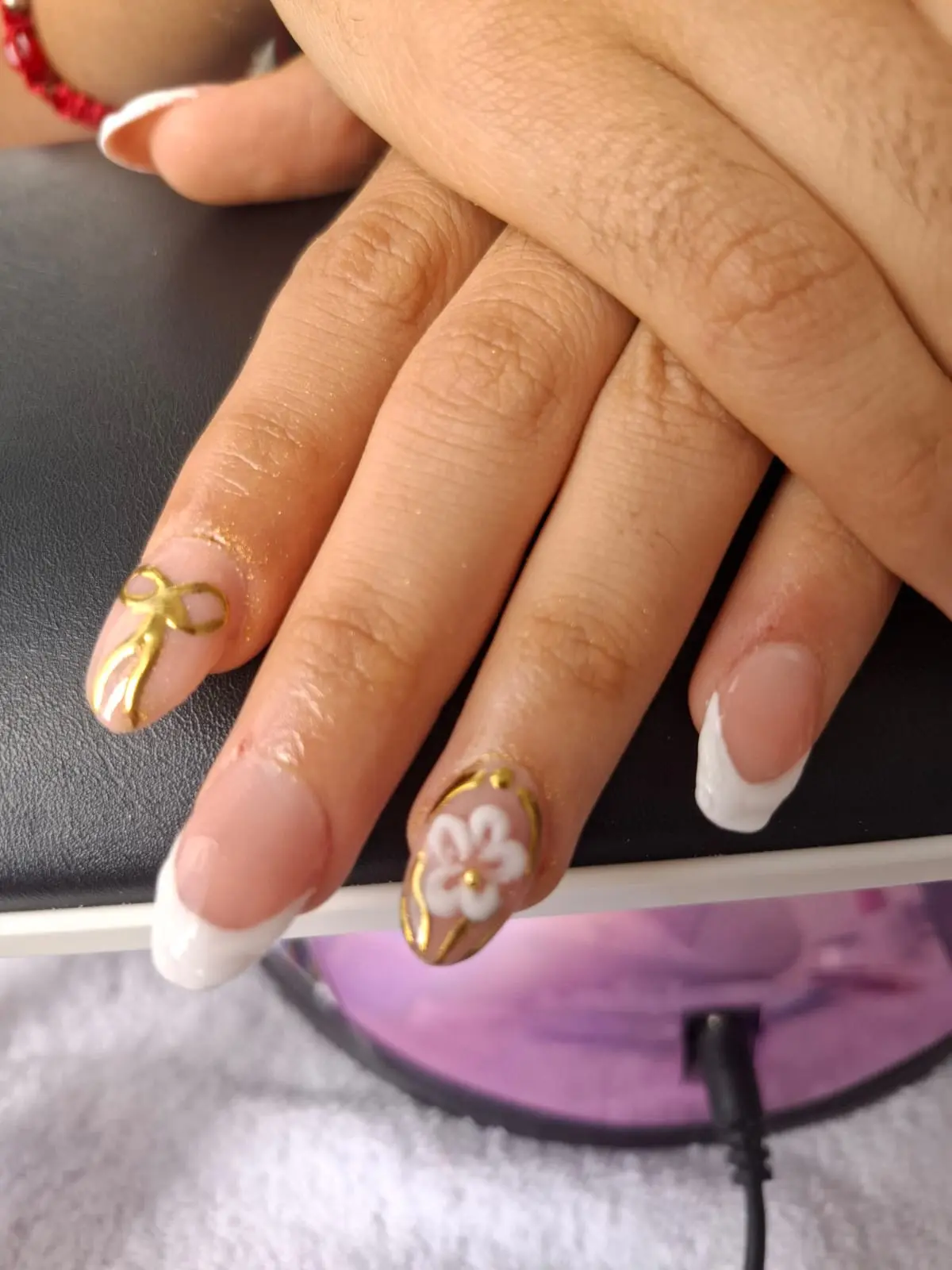 Diseño de uñas con base clara y moños dorados en 3D
