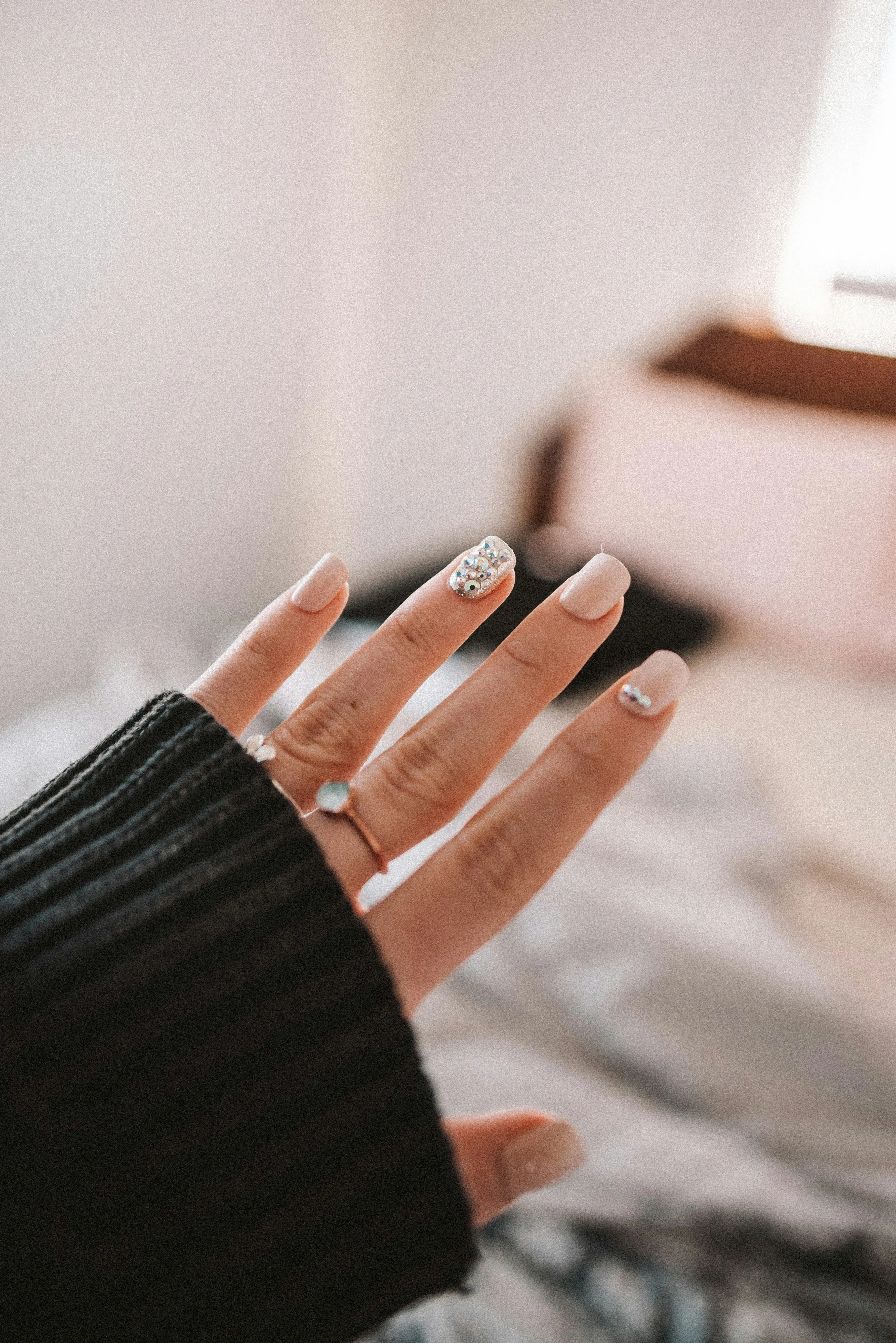 Uñas acrílicas nude con un diseño de pedrería brillante.