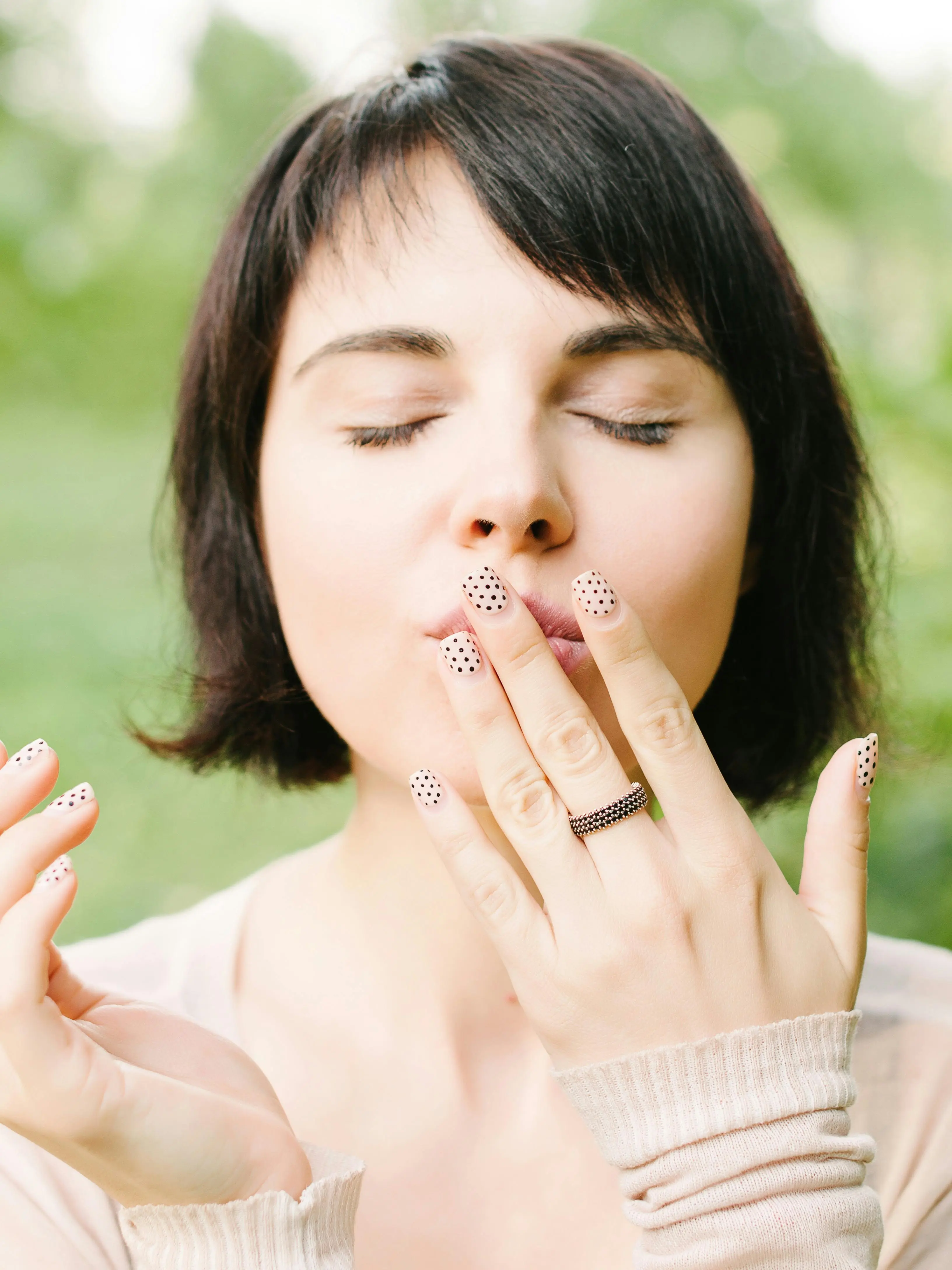 Mujer con un diseño de nail art de puntos sobre base nude.